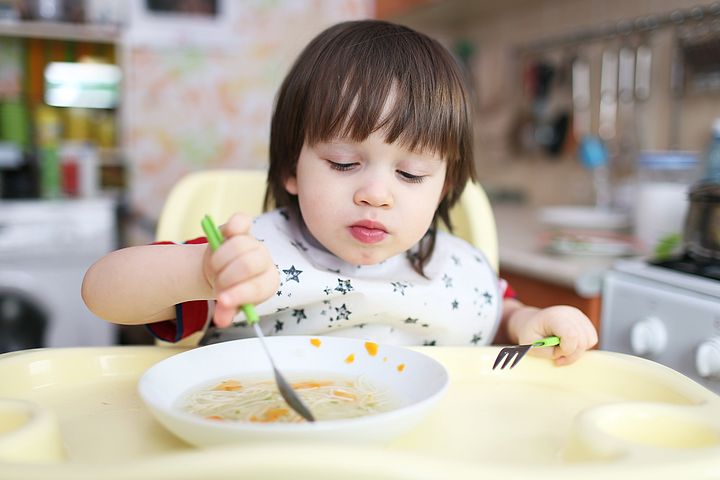 little boy eats soup at home